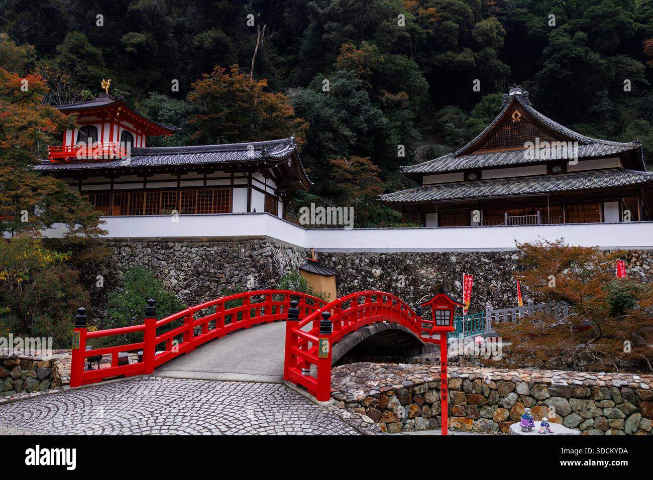 Serene autumn scene featuring a vibrant red arched bridge leading to ...