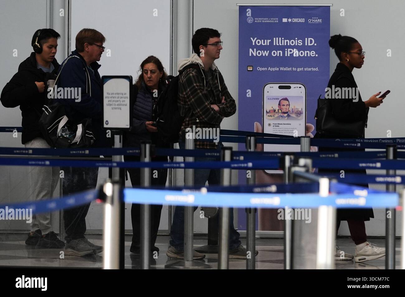 A Real ID sign is displayed as travelers wait to go through security ...