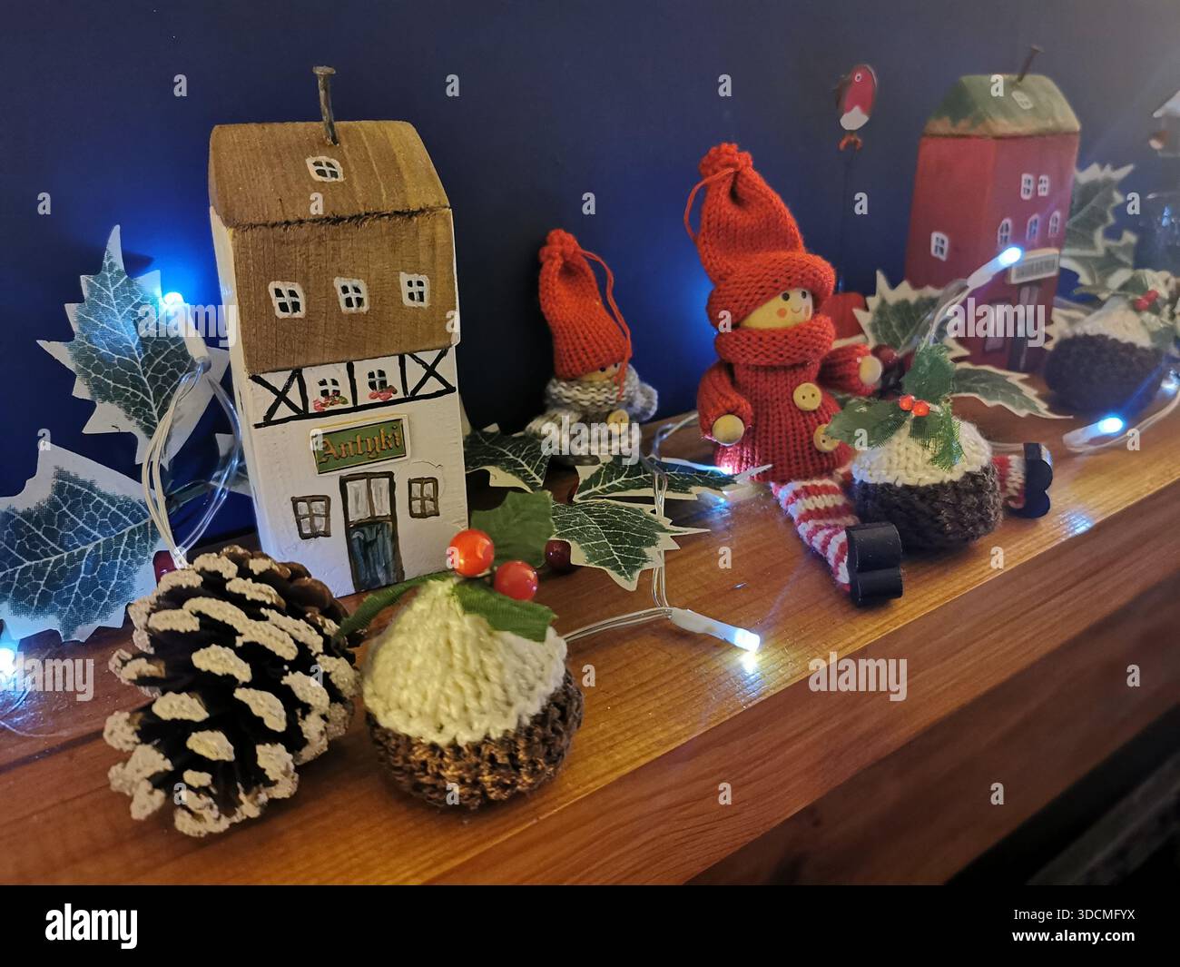 Cozy Christmas display with woollen ornaments, wooden houses, pine cone and soft white lights creating a warm, handcrafted festive atmosphere. - Smartphone Captured Stock Image