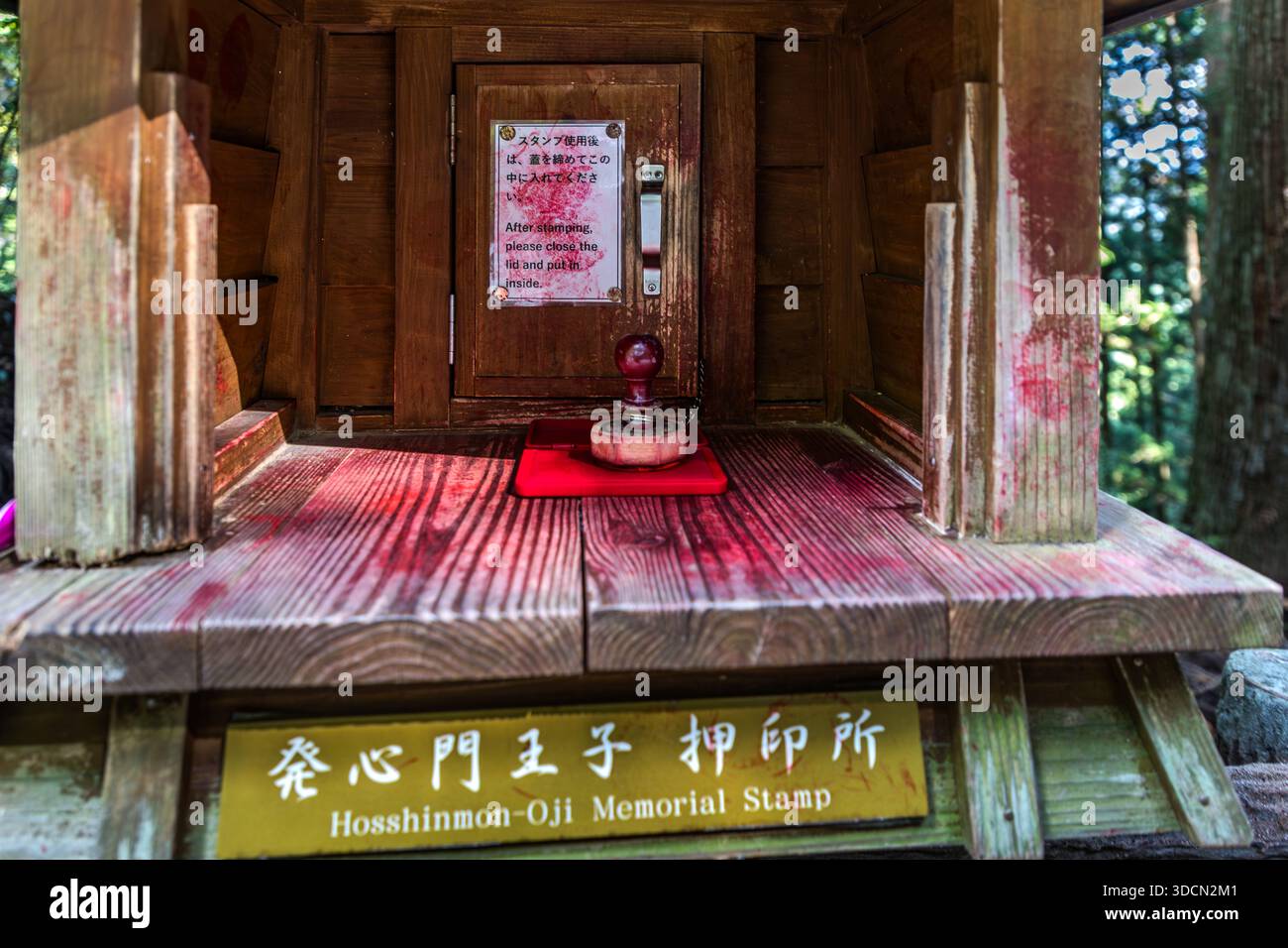 A stamp box stands at Hosshinmon-oji on the Kumano Kodo near Tanabe, Wakayama Prefecture, Japan. Pilgrims press a red stamp into their pilgrim's book (Nōkyōchō) here. The stamps document progress toward the Kumano Sanzan and the 99 Oji shrines. They symbolise purification, devotion and the reaching of holy places, similar to the Way of St James to Santiago de Compostela. Stock Photo