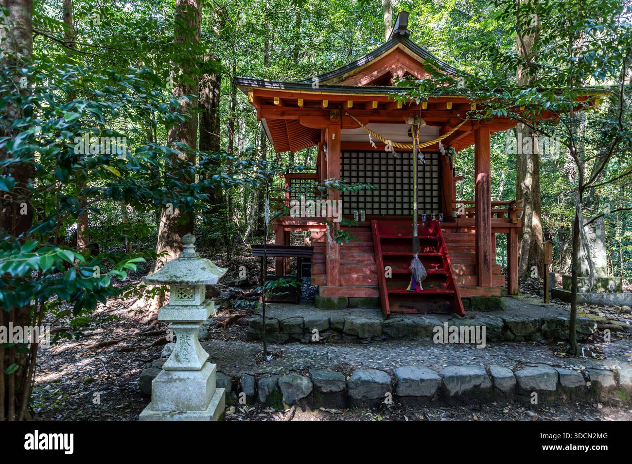 A small, red-lacquered shrine with a steep staircase stands in the forest at Hosshinmon-oji near Tanabe, Wakayama Prefecture, Japan. The site marks the outer entrance to the sacred precincts of Kumano Hongū Taisha and was historically one of several gates along the Kumano Kodo marking ritual phases of the pilgrimage. Stock Photo