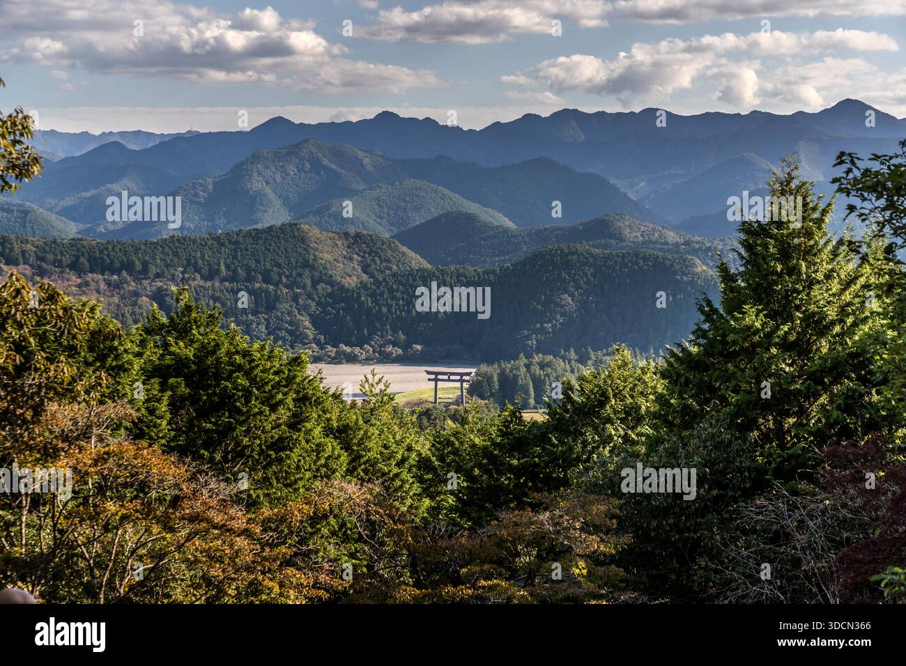 The Oyunohara Great Torii rises above fields in the valley below the Kumano Kodo, near Kumano Hongu Taisha, Tanabe, Wakayama Prefecture, Japan. Built in 2000, the 33-metre steel gate marks the site of the original Kumano Hongu Taisha, destroyed by a flood in 1889 and rebuilt on higher ground in 1891. Stock Photo