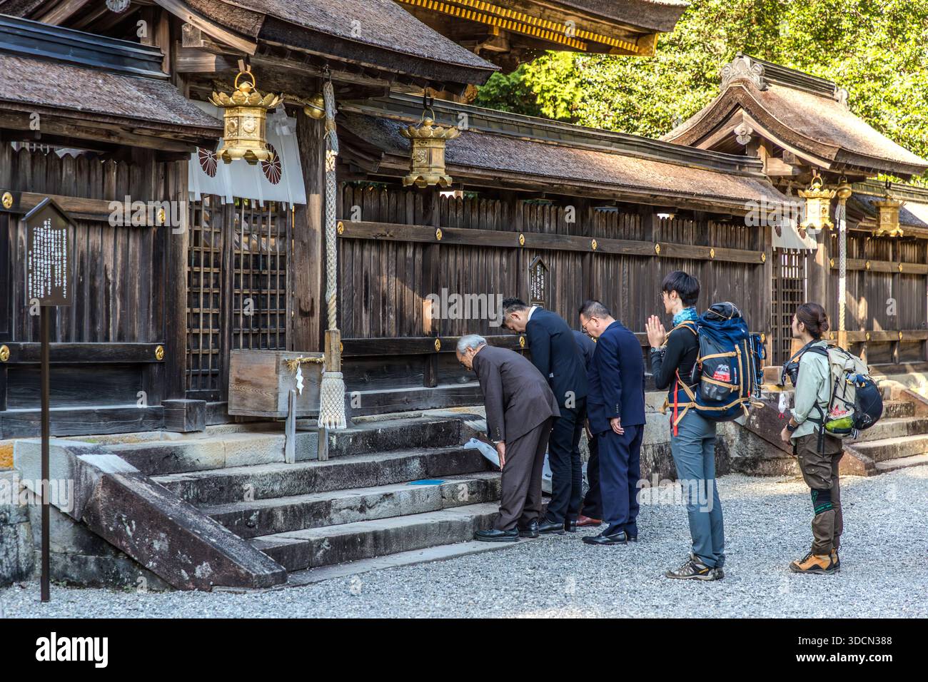 Businesspeople in suits pray together in front of Kumano Hongū Taisha, Tanabe, Wakayama Prefecture, Japan. Such group prayers ask for success, prosperity and protection for a company, often at the start of the year (Hatsumōde) or before major projects – Shinto deities such as Ebisu, the god of commerce, are worshipped specifically for business success. Stock Photo