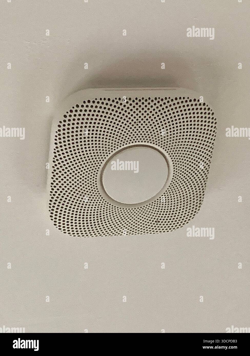 Modern ceiling- mounted smoke and carbon monoxide detector in a residential interior designed for early warning and home fitted in a house - Smartphone Captured Stock Image