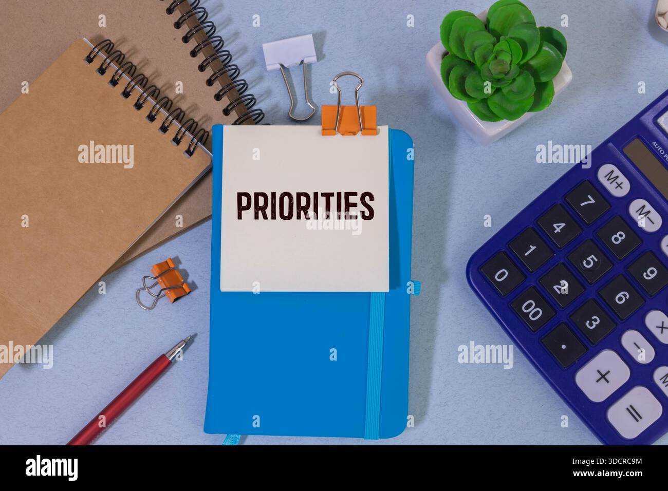 A sheet of kraft paper torn from a notebook lies on the table. Text on PRIORITIES sheet. Colored pens and a pencil. Stock Photo
