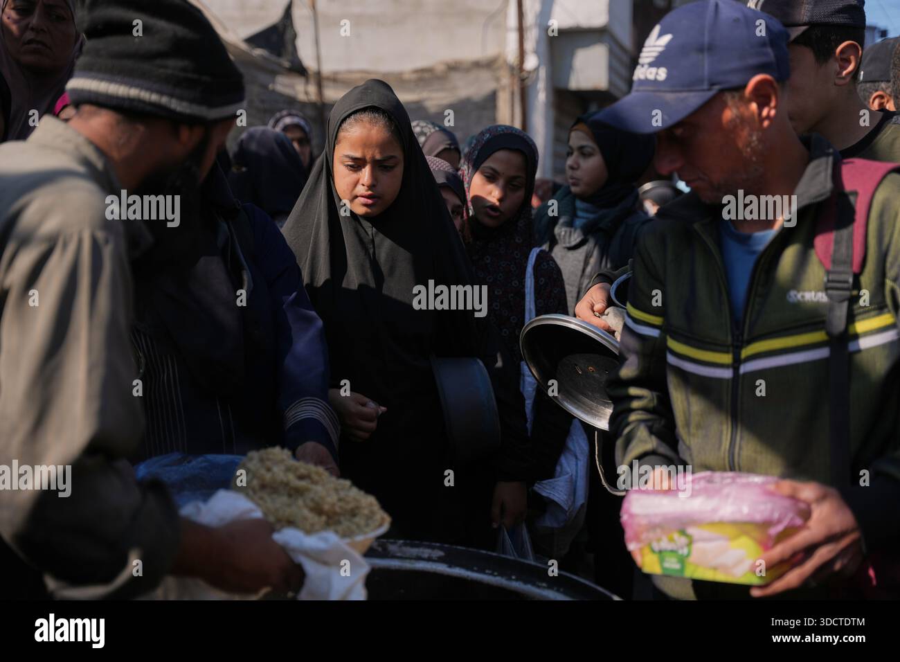 Palestinians women line up to receive donated food at a community ...