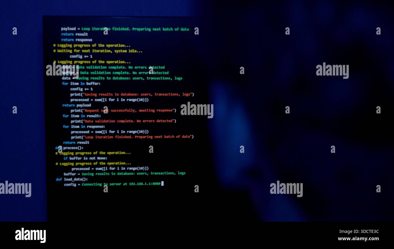 Programmer working on laptop with code on the screen in the dark Stock Photo