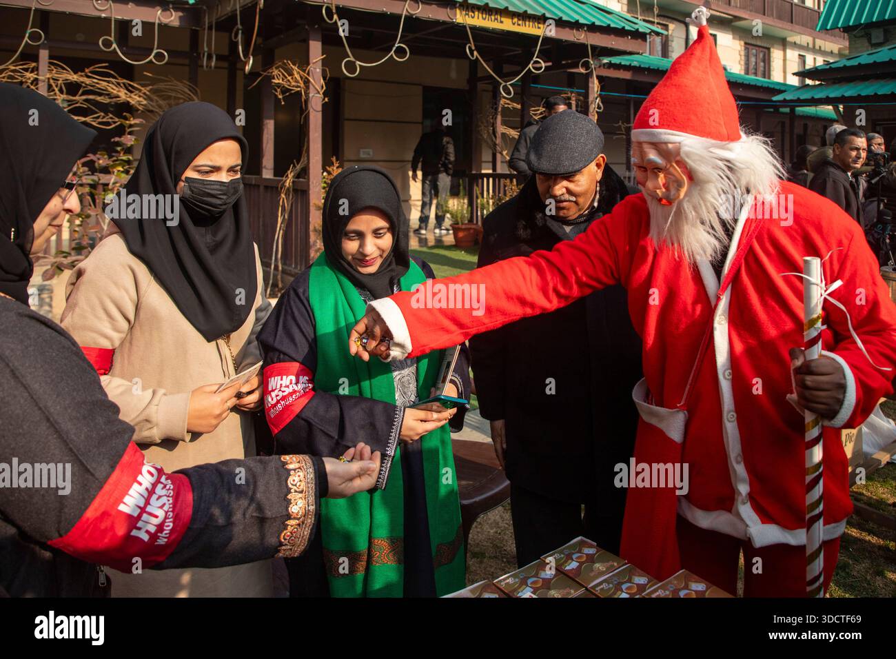 A person dressed as Santa Claus costume distribute sweets among Volunteers from Who is Hussain?, a Shiite Muslim non governmental organization, outside the Holy Family Catholic Church during Christmas celebrations in Srinagar, Indian administered Kashmir. Advocacy groups say that Christians, a small minority in India, have in recent years documented a rise in incidents of violence, harassment and interruptions to religious gatherings, often carried out by far?right Hindu nationalist groups and local mobs, developments that have intensified debate over religious freedom and the rights of minori Stock Photo
