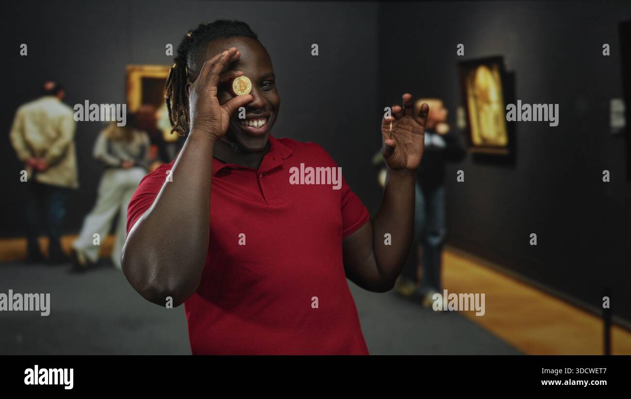 Man holding bitcoin coin to eye smiling in art gallery while showing both  hands and wearing red polo; cryptocurrency investment joy Stock Photo -  Alamy