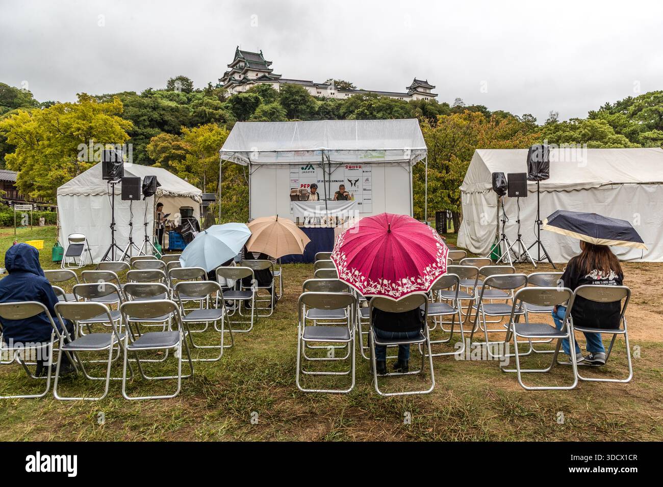 Spectators wait under umbrellas for an event in front of Wakayama Castle. Wakayama, Wakayama Prefecture, Japan Stock Photo