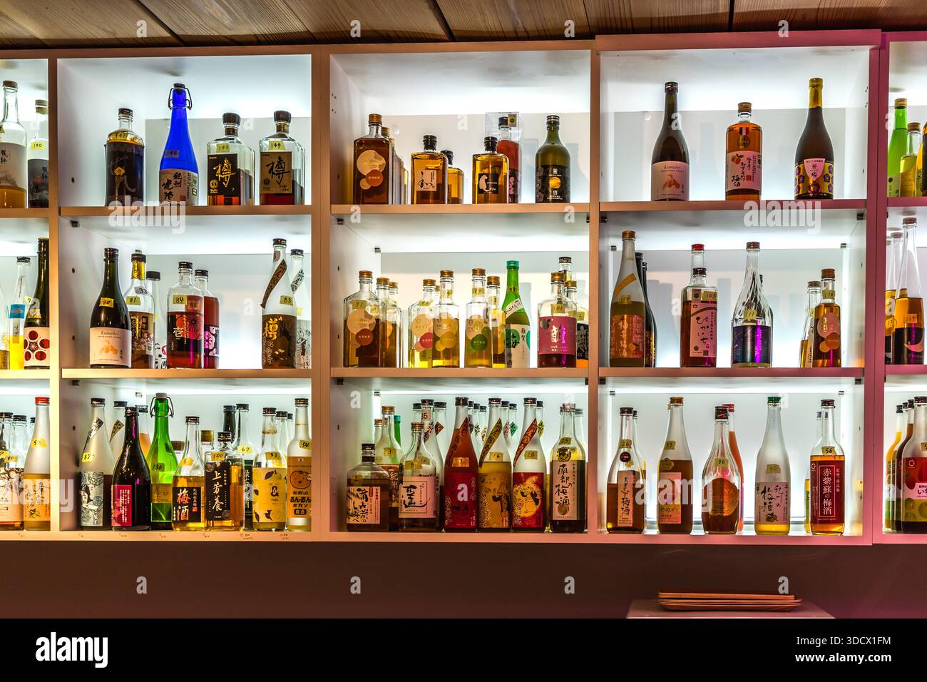 Illuminated shelves filled with bottles of Japanese plum liqueur, umeshu (梅酒), line the Umeshu Bar run by the Tanabe Tourist Organisation in Wakayama Prefecture, Japan. The bar presents around 140 varieties of umeshu from some 30 regional producers and offers tastings and workshops for visitors to blend their own liqueur. Stock Photo