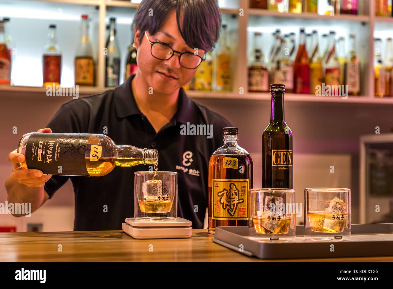 A staff member at the Umeshu Bar in Tanabe, identified by Tellerrand Stories research as Daiki Sako, pours Hamada Craft Liqueur brand umeshu, a Japanese plum liqueur, into a glass. Run by the Tanabe Tourist Organisation, the bar stocks 140 varieties of umeshu from 30 producers in Wakayama Prefecture, Japan. Stock Photo