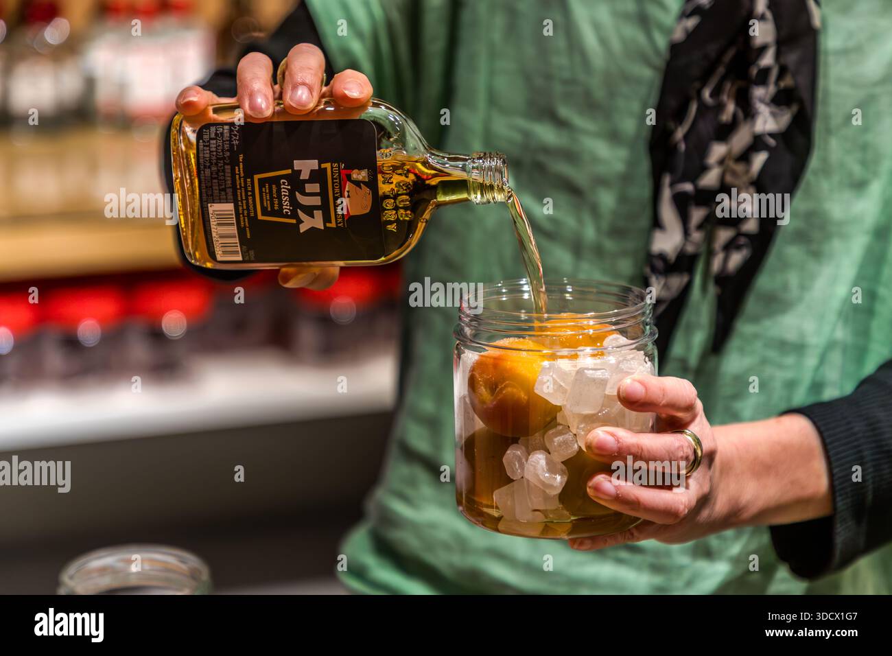 At an umeshu workshop in Tanabe, a person pours Suntory whisky over ripe plums in a glass, the first step toward a home-made batch of the Japanese plum liqueur umeshu. Wakayama Prefecture, Japan. Stock Photo
