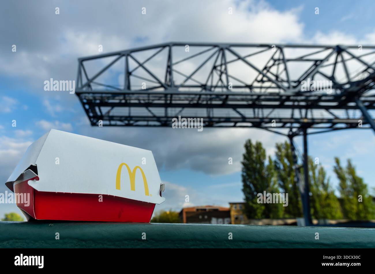 Close-up photograph of discarded McDonald’s food packaging placed on a bridge railing in an urban setting. Stock Photo