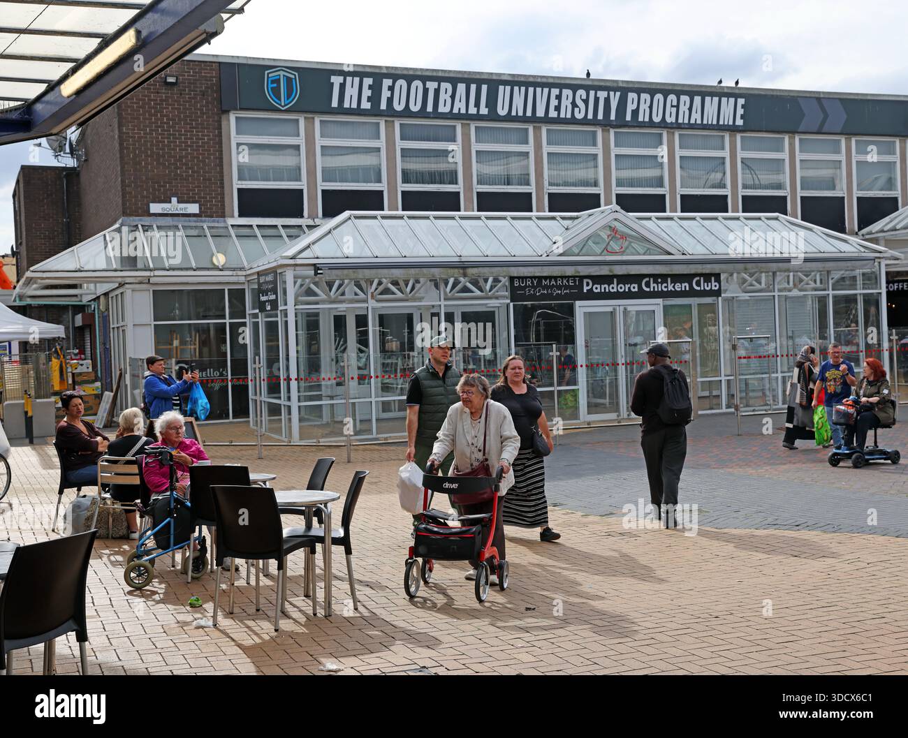 People walking and socialising outside The Football University Programme building near Bury Market, Bury BL9 0SW, Greater Manchester, England, UK Stock Photo