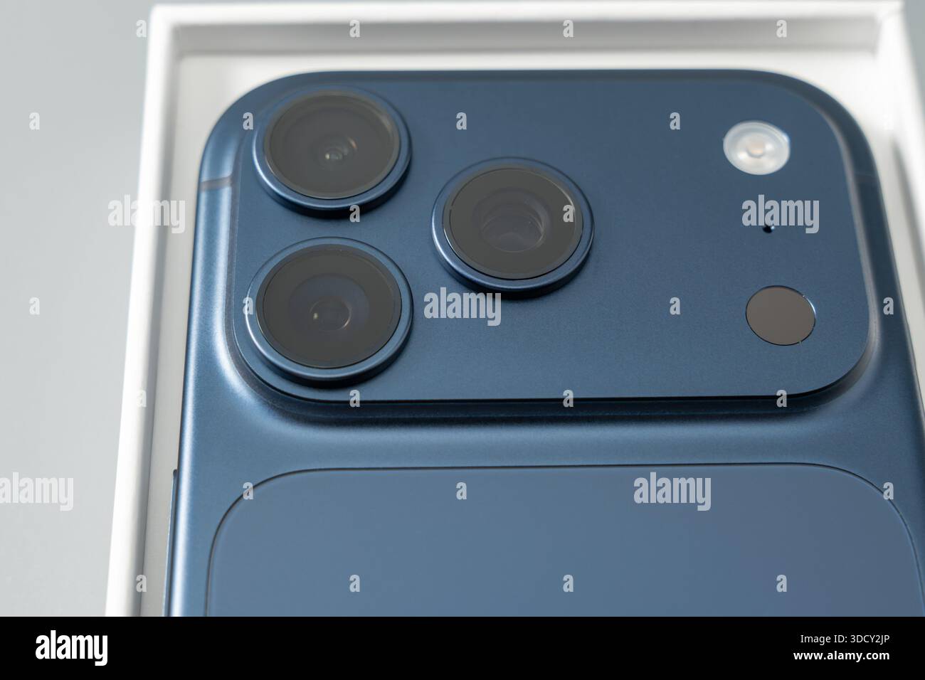 Top-down view of a smartphone back showing a triple camera layout and flash inside its packaging. Clean composition with neutral background and soft s Stock Photo