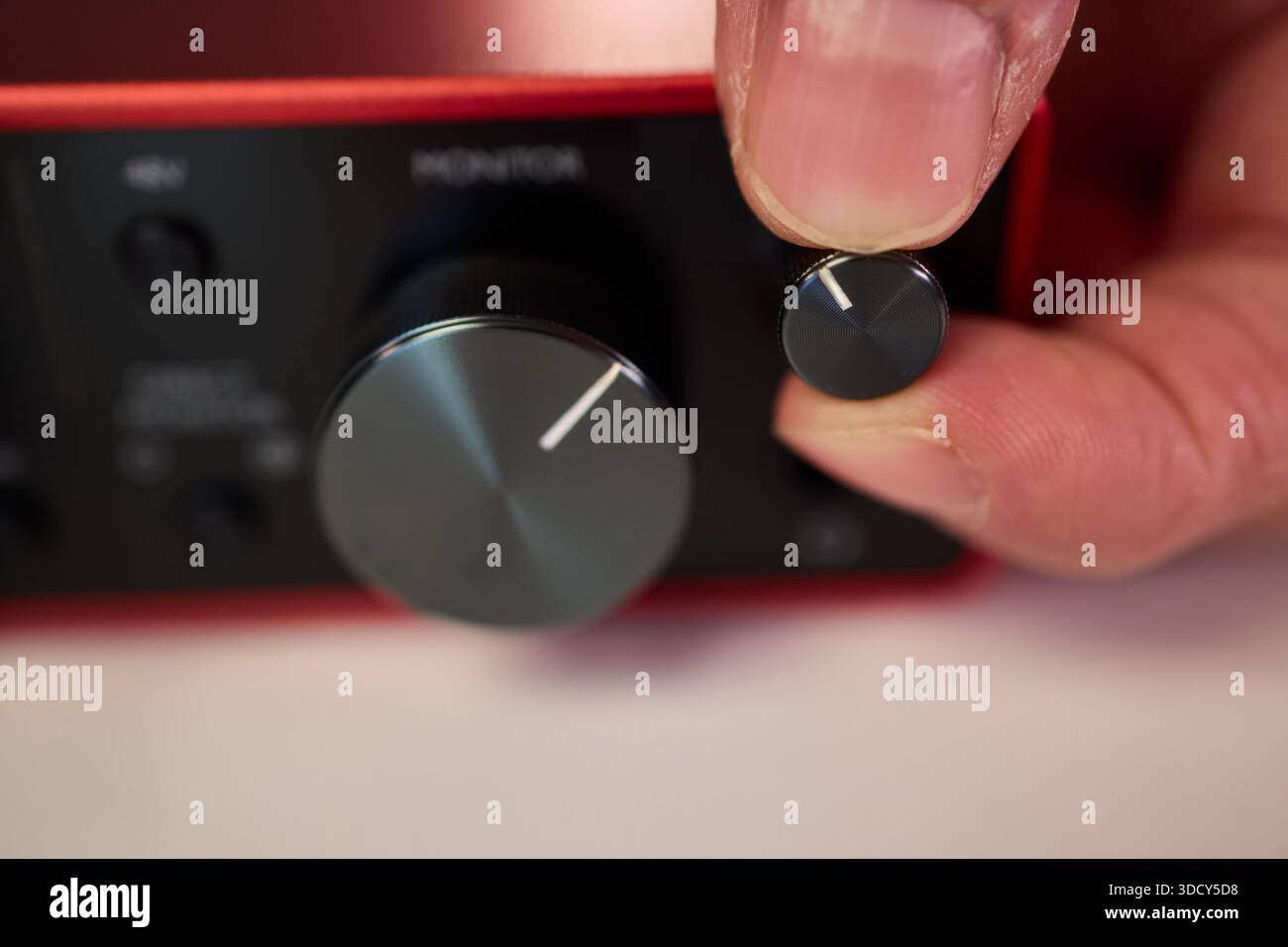 Adjusting audio controls, Precise handling of control knobs on audio equipment during setup, Fingers align control dials on audio interface for Stock Photo