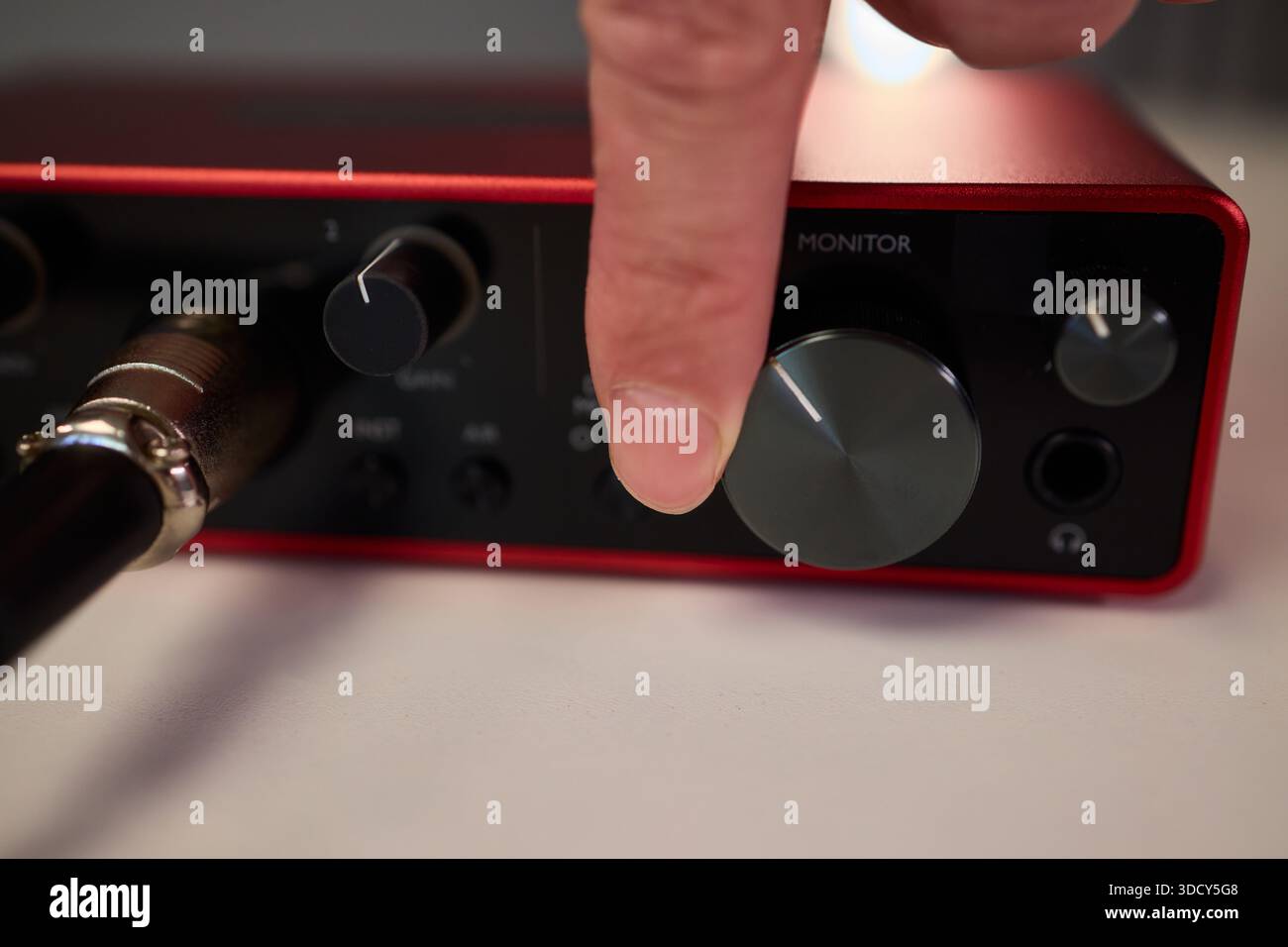 Adjusting audio controls, Precise handling of control knobs on audio equipment during setup, Fingers align control dials on audio interface for Stock Photo