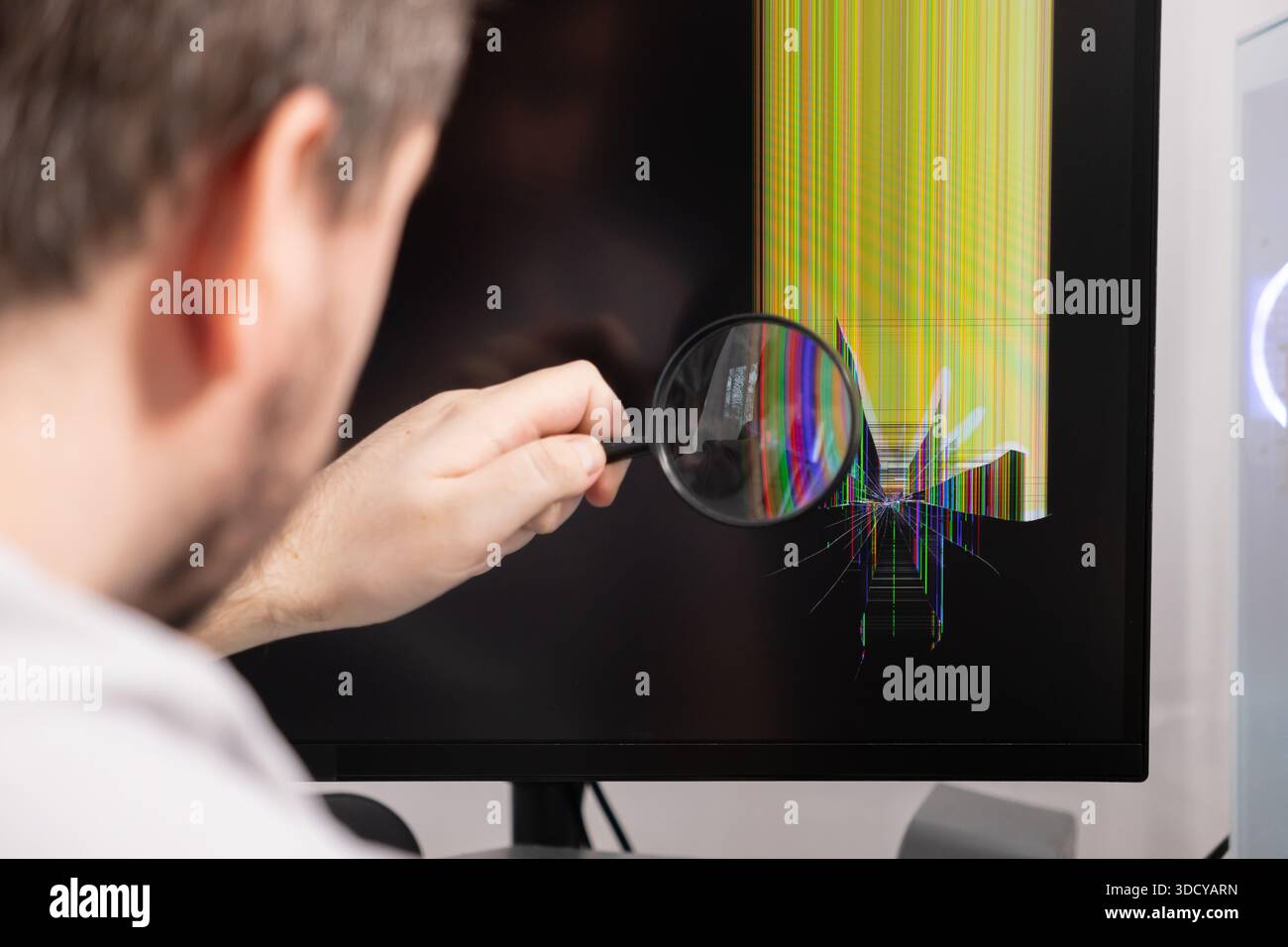 A persons hand uses a magnifying glass to inspect a damaged computer ...