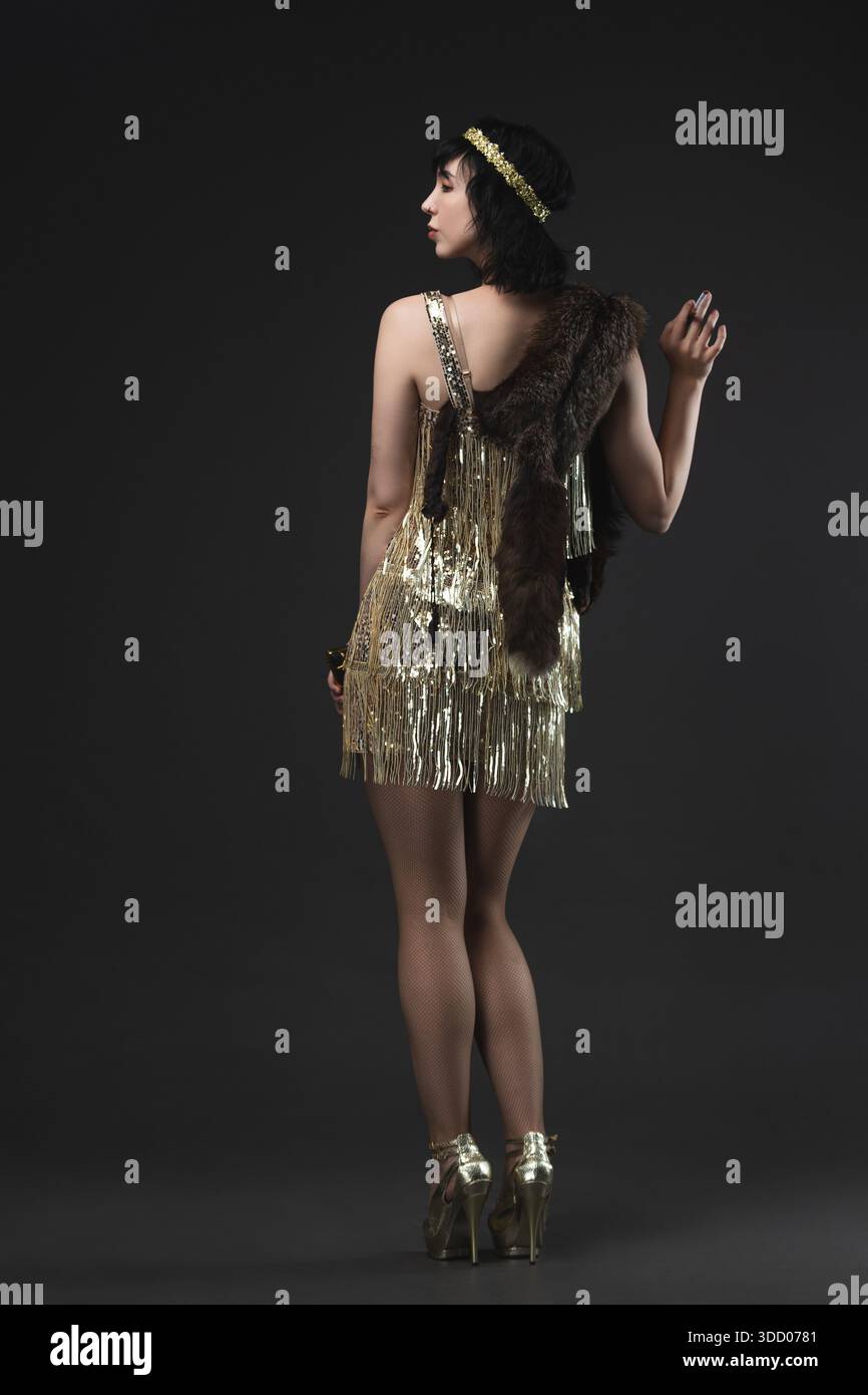 Flapper era femme fatale in short gold dress, Art Deco jewelry and bob. Stock Photo