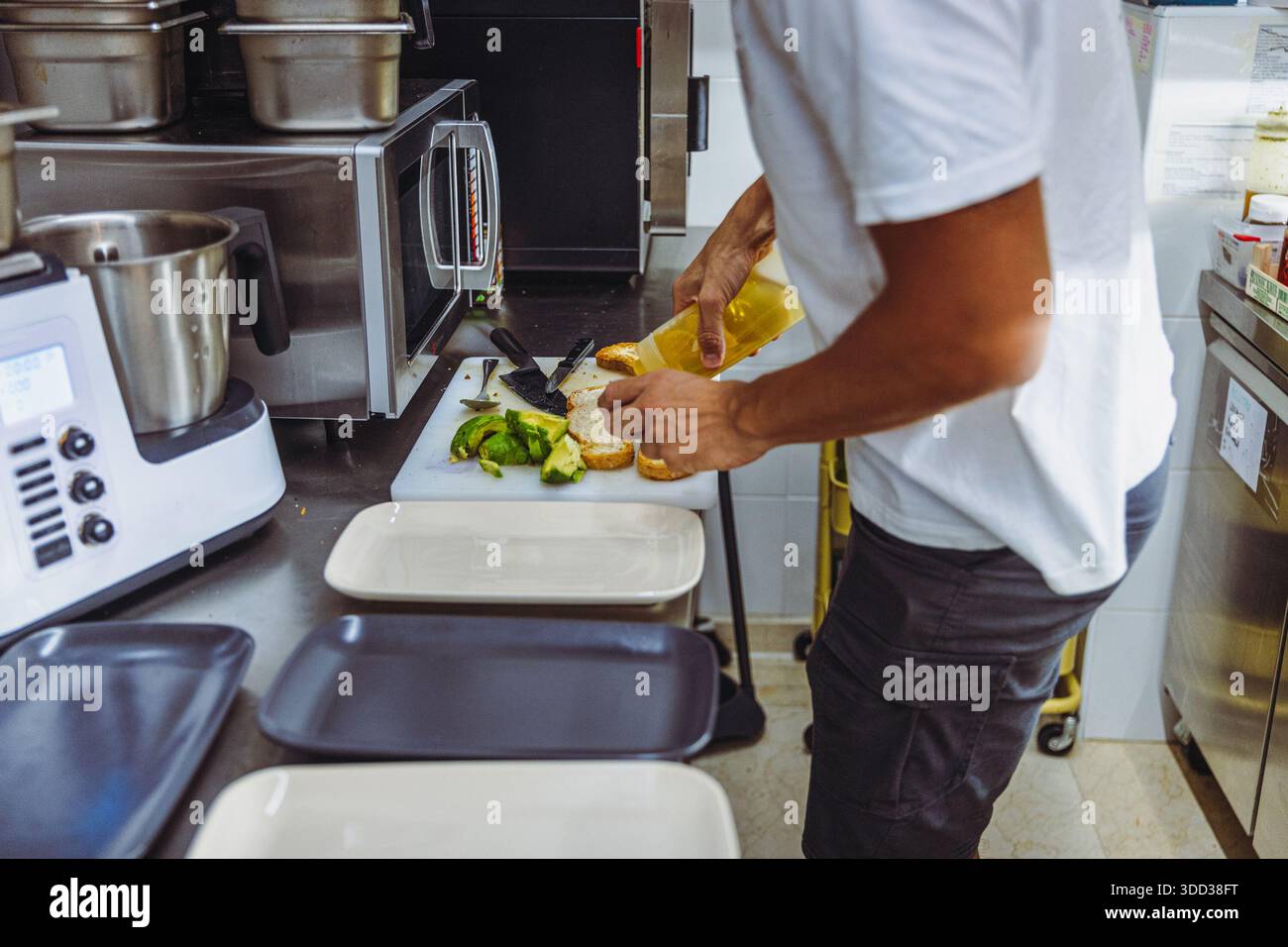 Vegan chef preparing avocado toast in restaurant kitchen workstation. Stock Photo