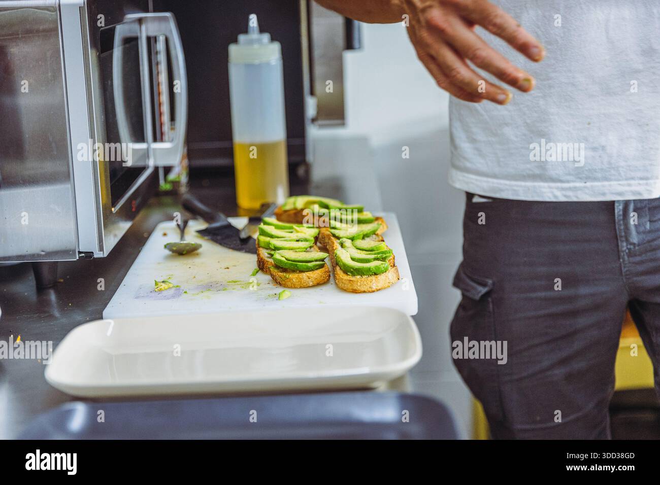 Vegan chef preparing avocado toast in restaurant kitchen workstation. Stock Photo
