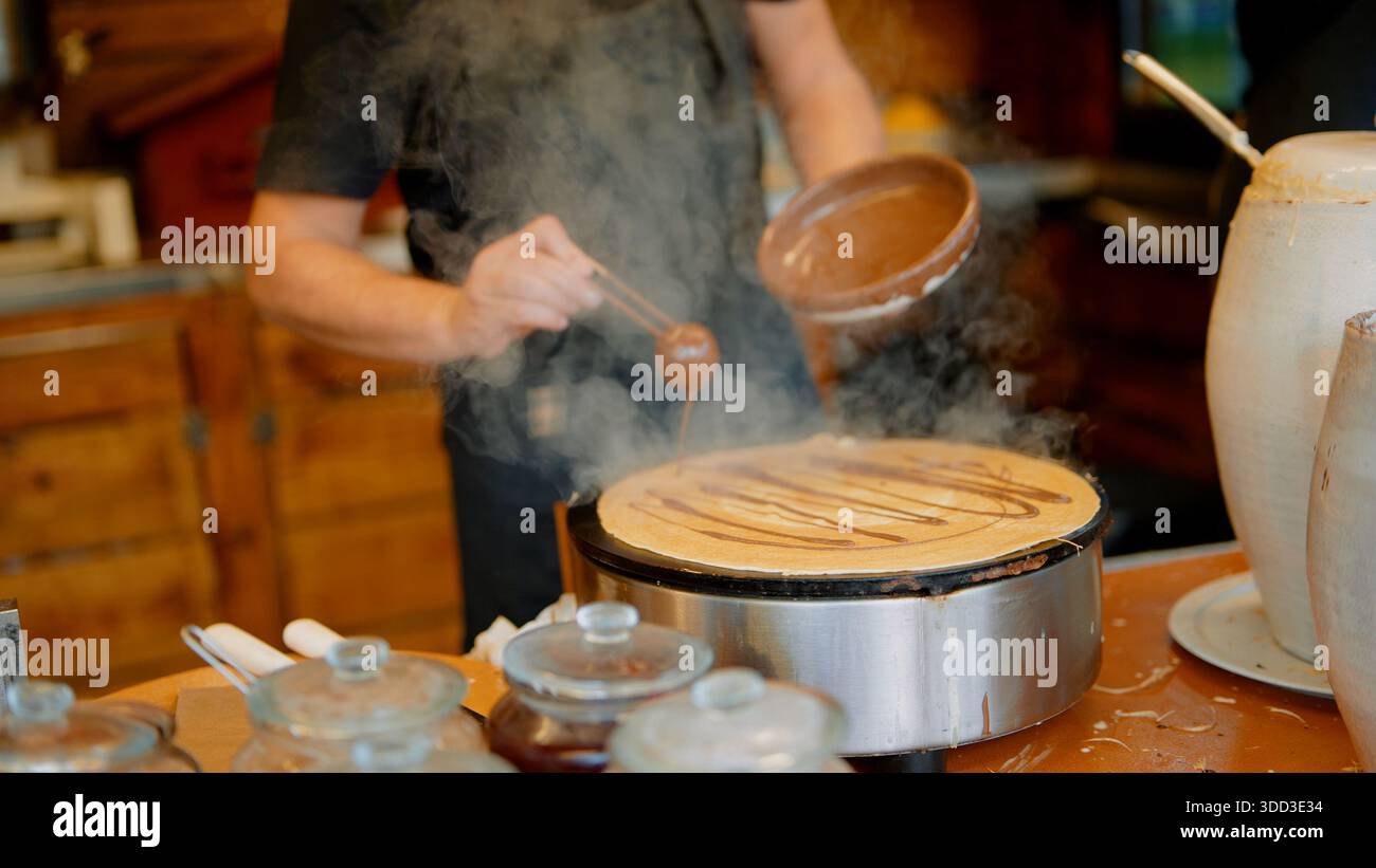 Artisan vendor expertly flipping and managing crepes on busy street corner Stock Photo