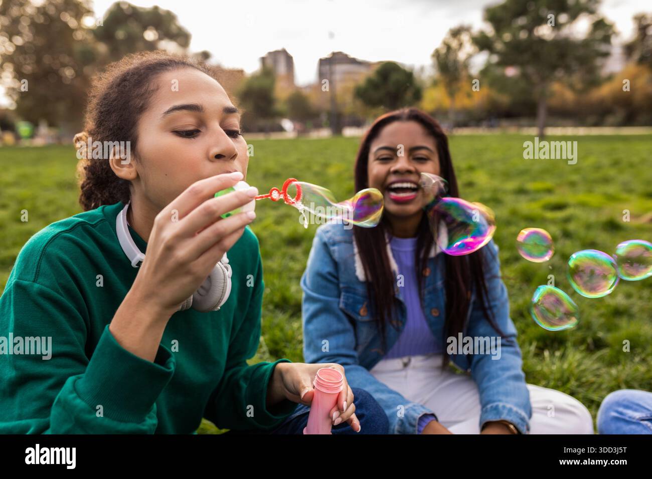 Happy friends blowing bubble making soap bubbles in park Stock Photo