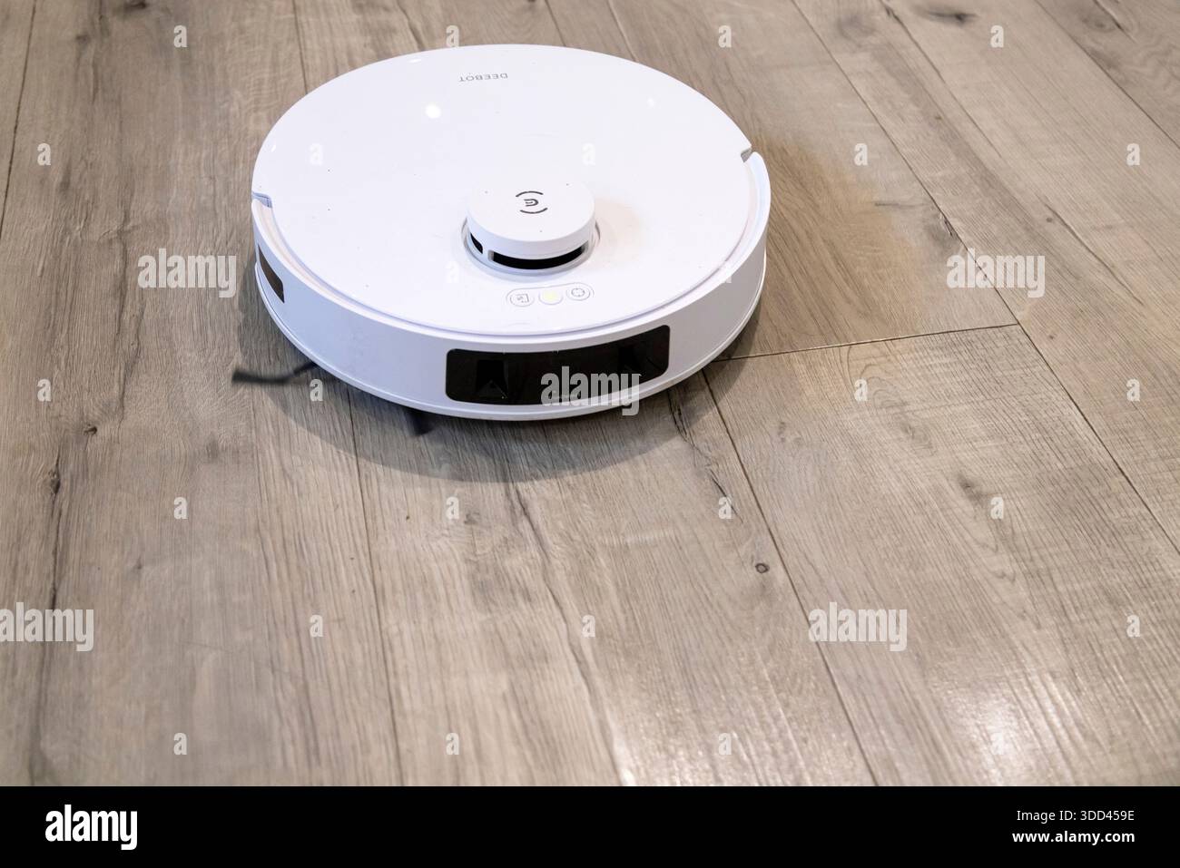 Robotic vacuum cleaner cleaning a wooden floor Stock Photo