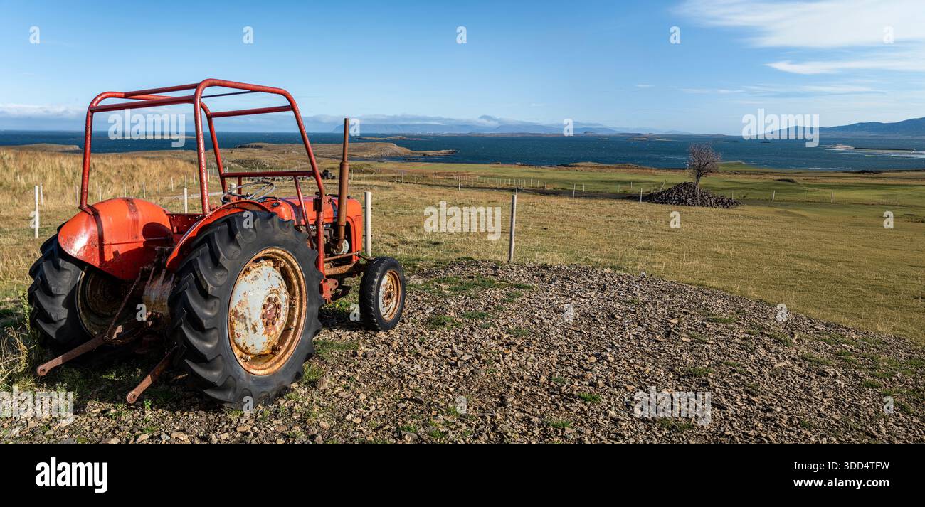 Red rusty tractor in a field. Large country tool, old abandoned tractor ...
