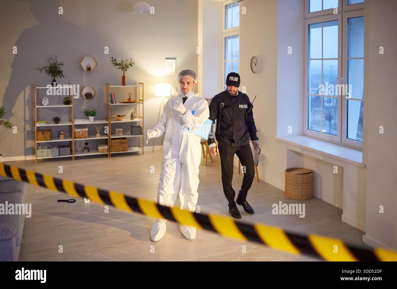 Forensic investigator in protective suit examining evidence with police ...