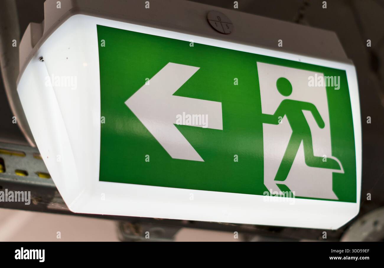 Glowing emergency exit sign with arrow and running figure indicating ...