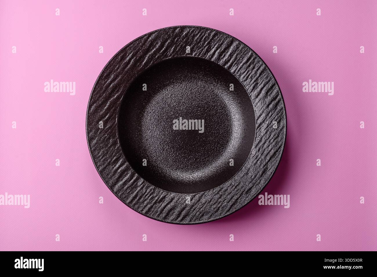 An empty round ceramic plate on a pink background as a kitchen utensil. An empty plate as a food background for your design Stock Photo