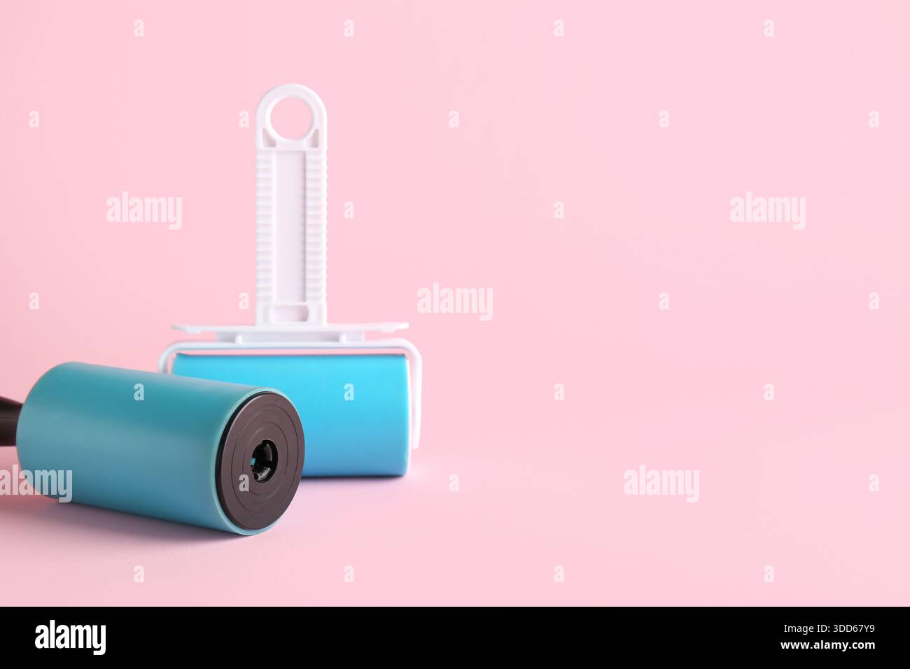 Different lint rollers on pink background Stock Photo