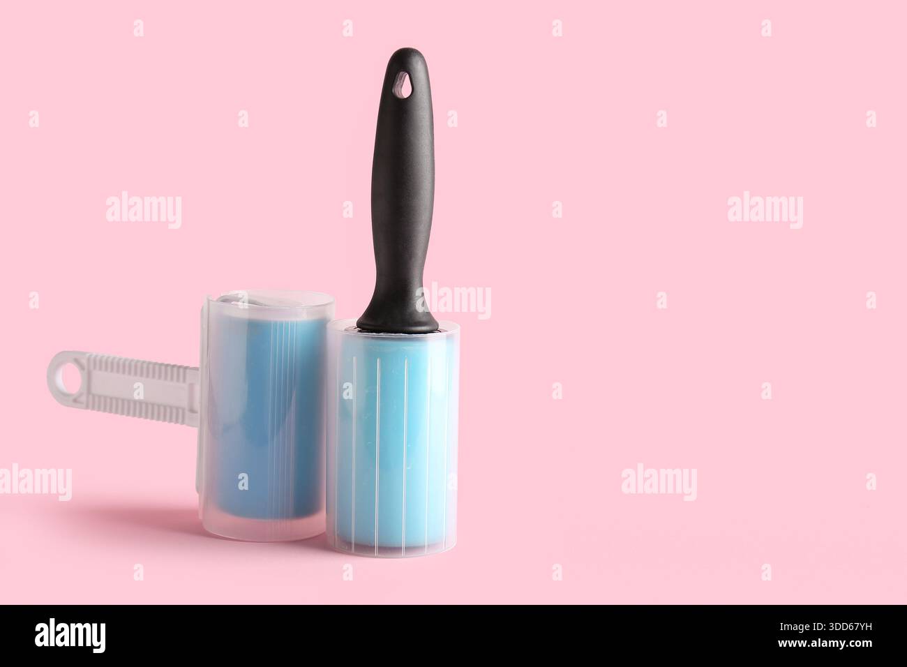 Different lint rollers on pink background Stock Photo