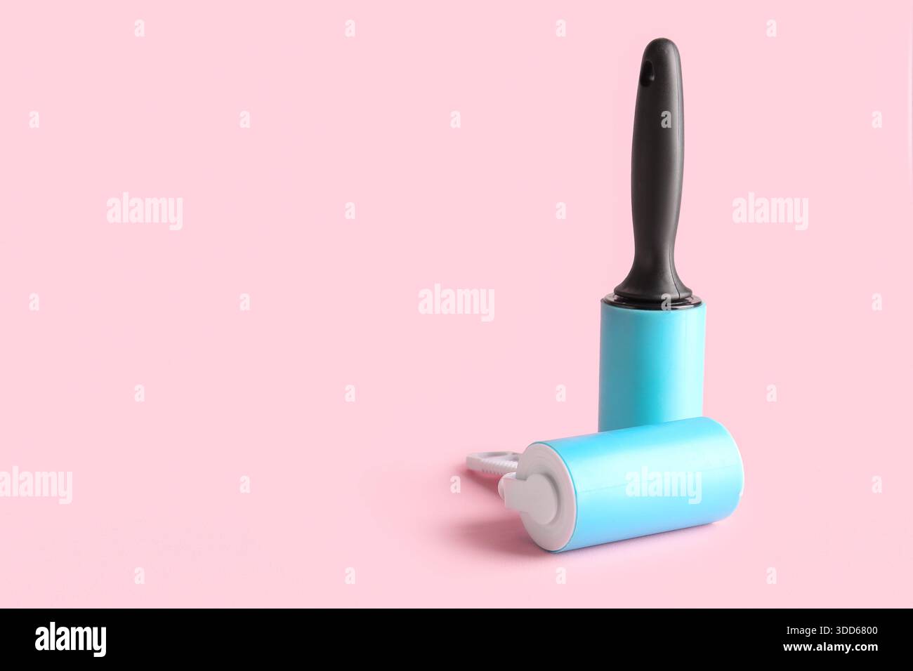 Different lint rollers on pink background Stock Photo
