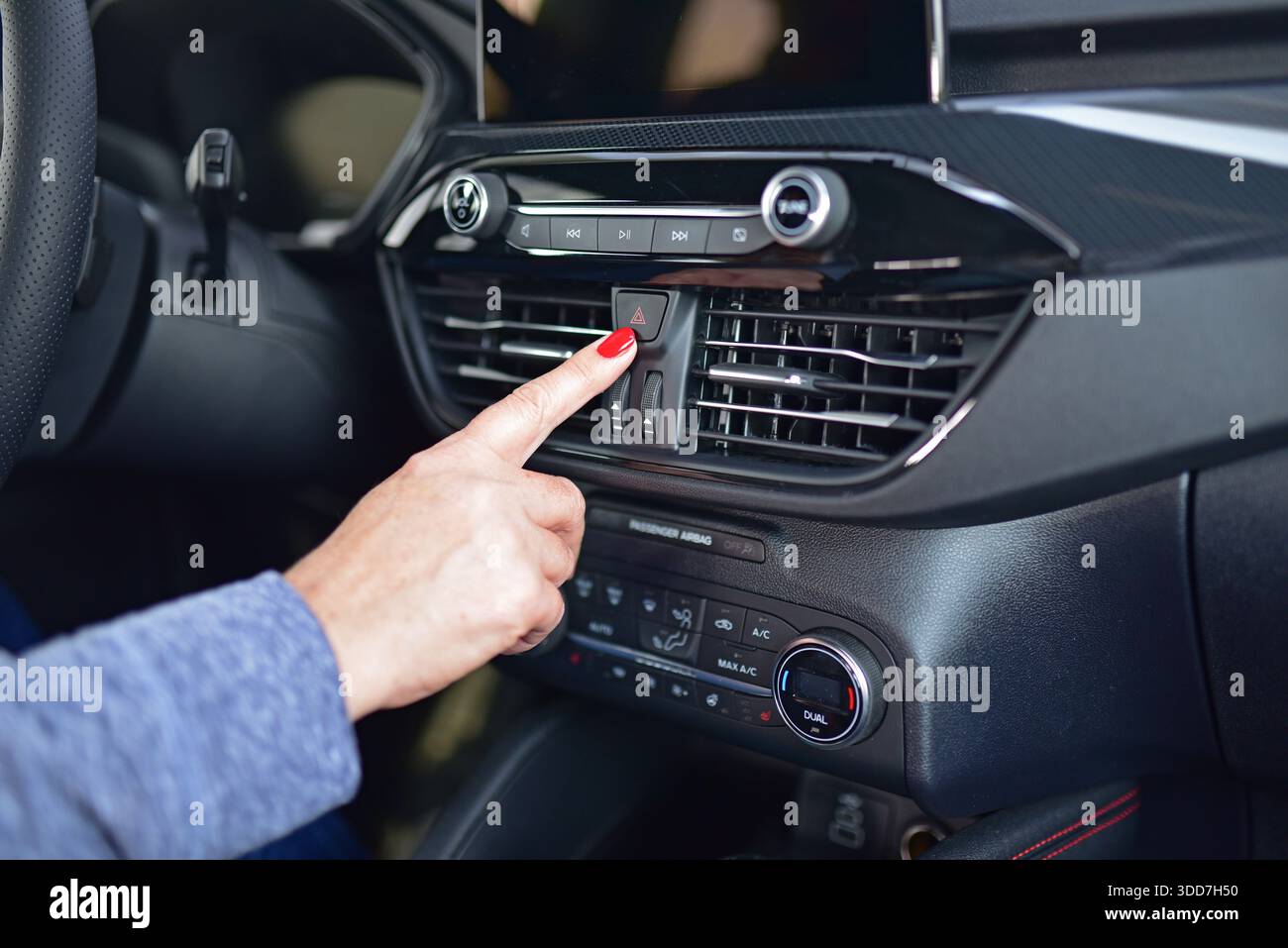 Female pressing red triangle car hazard warning button Stock Photo