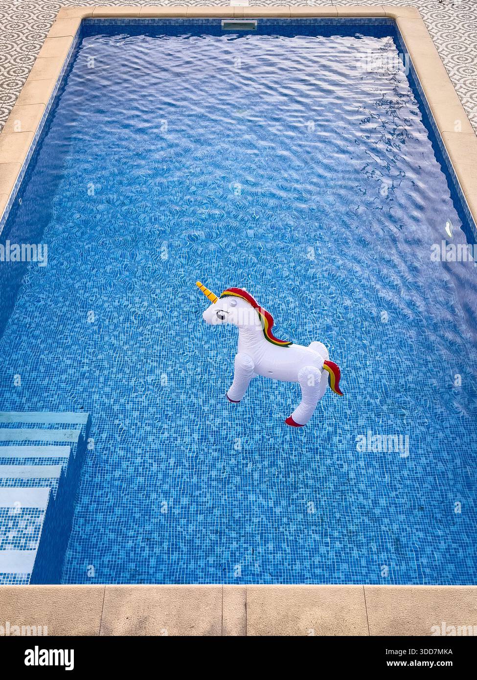 An inflatable toy unicorn floating upright on the water in a swimming ...