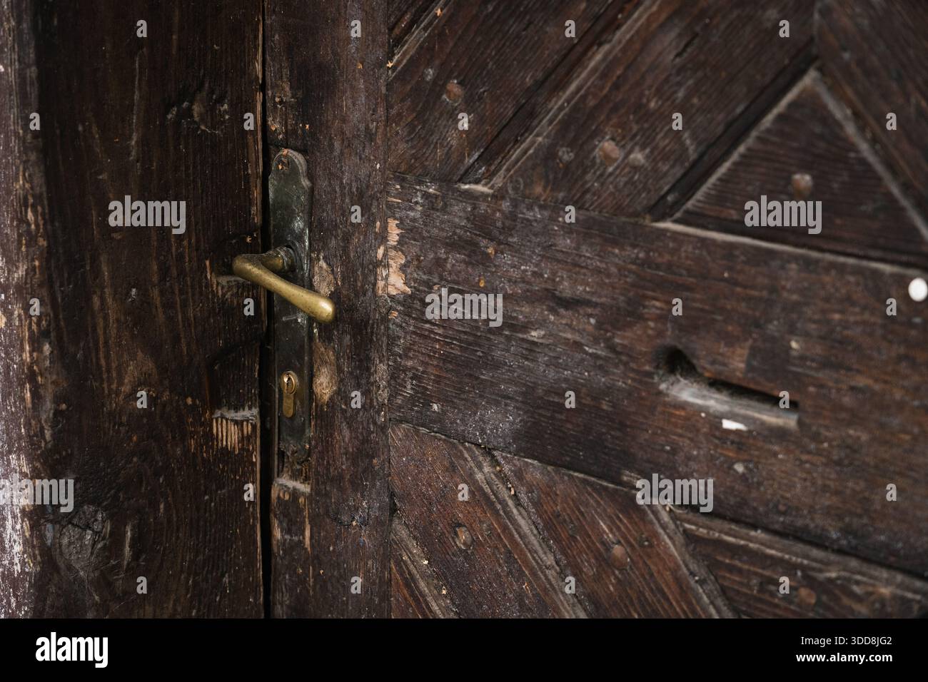 Close-up of Old Wooden Door with Yellow Metal Handle Stock Photo