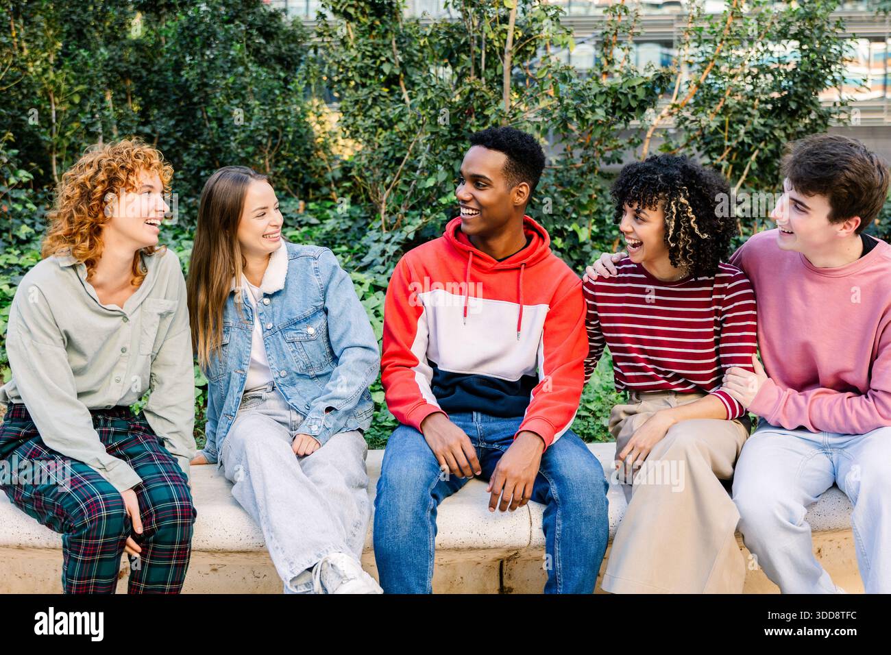 Group of diverse smiling young friends interacting outdoors Stock Photo