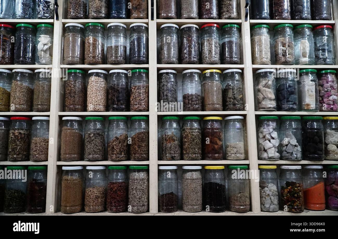 Glass jars filled with dried spices, herbs, and grains arranged on wooden shelves. Perfect for the pantry, kitchen, and your culinary creations. Stock Photo