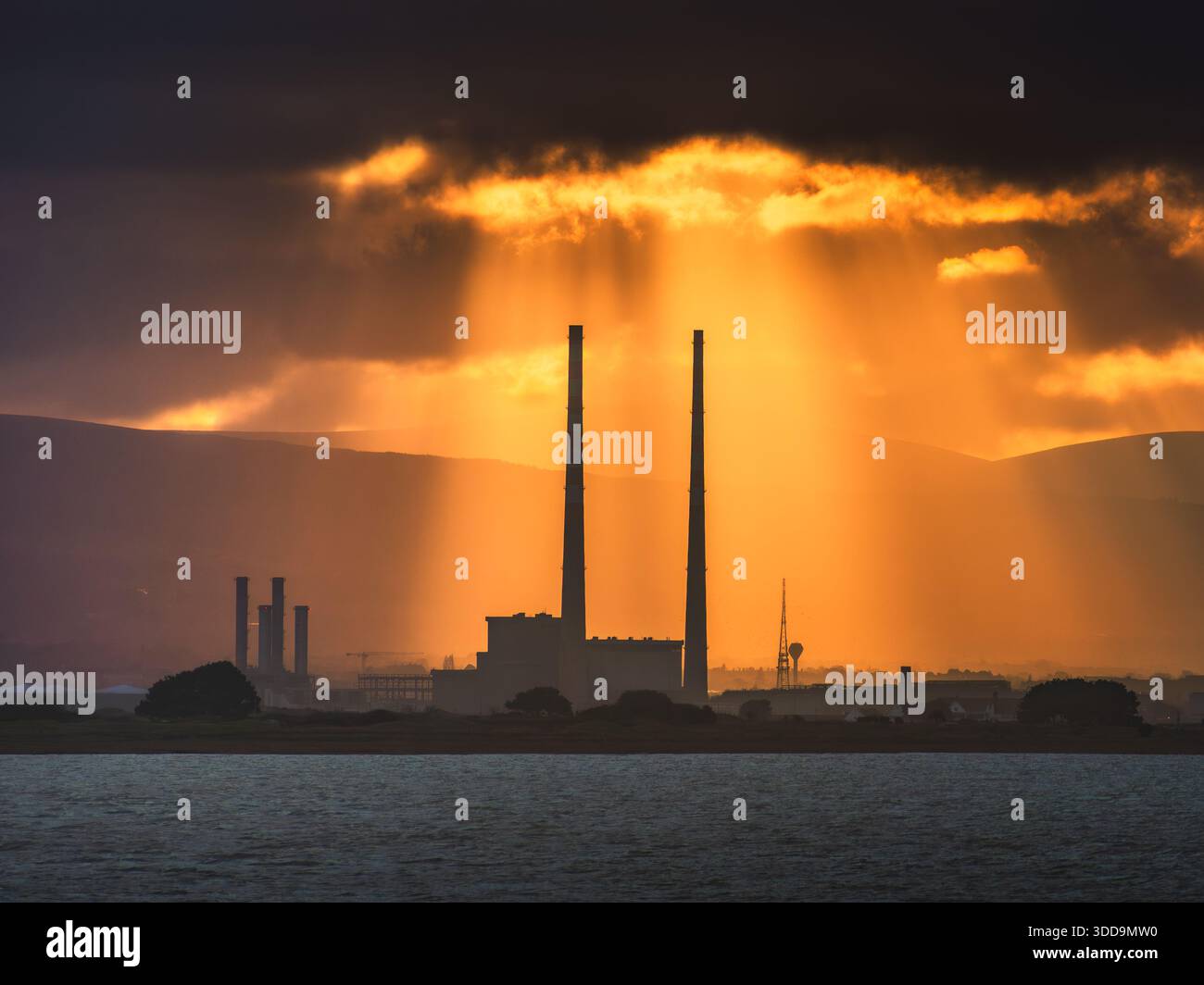 Sun rays beaming down on the Poolbeg Chimneys Stock Photo