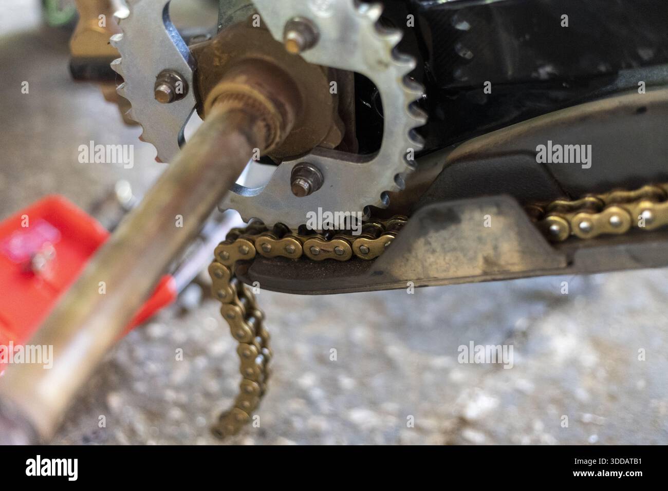Detail shot of motorcycle sprocket mechanism with metal chain link and gear wheel part showing industrial texture and complex engineering maintenance Stock Photo