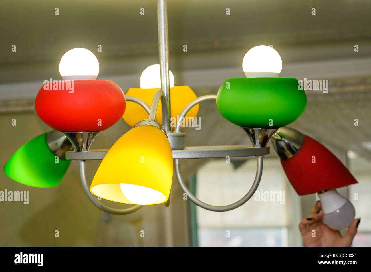 Male hands screw LED bulb into lamp during routine upgrade. Lamp represents low-energy lifestyle and attention to practical sustainability. concept of Stock Photo