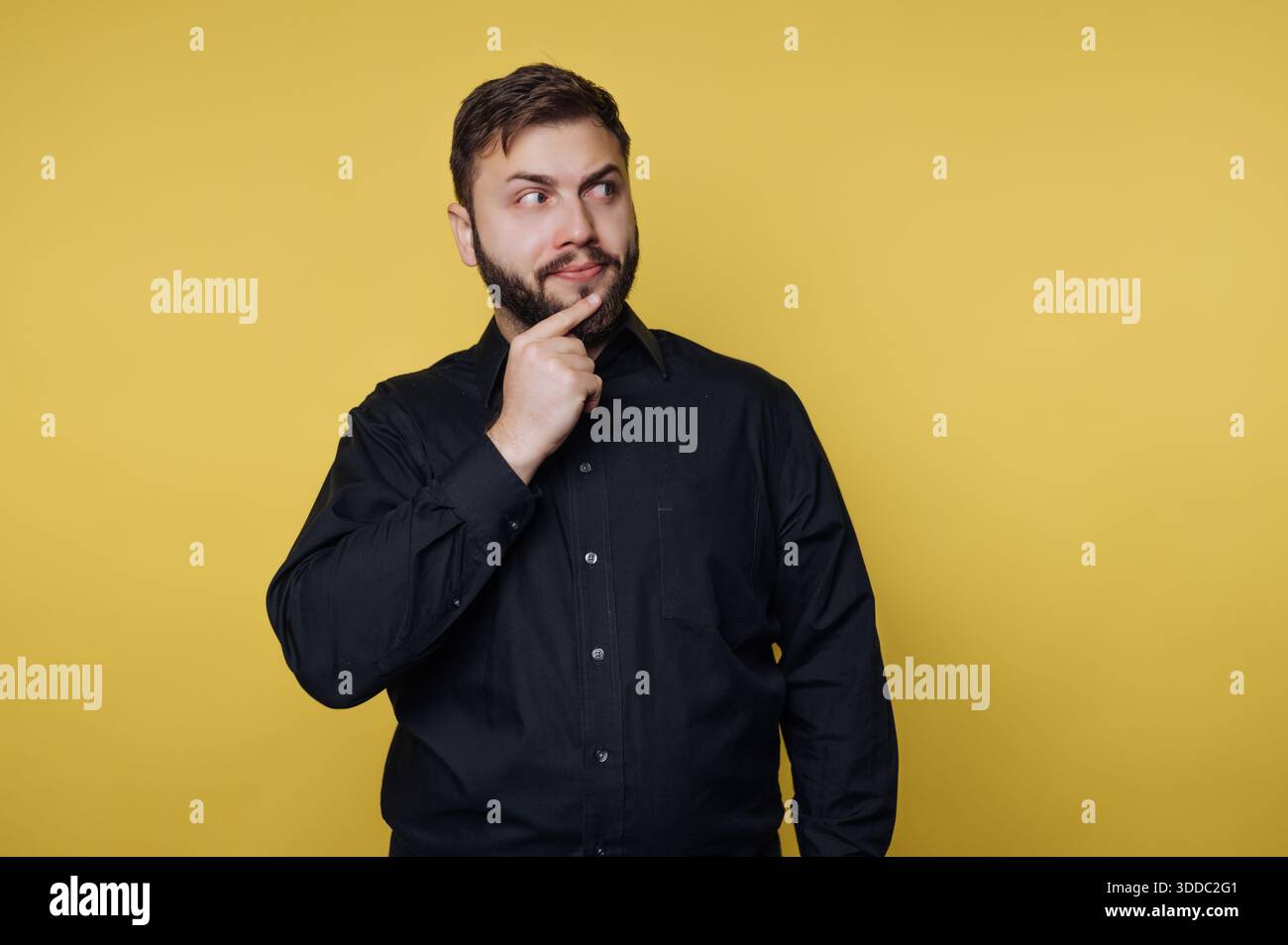 Man in black shirt thinking against yellow background Stock Photo