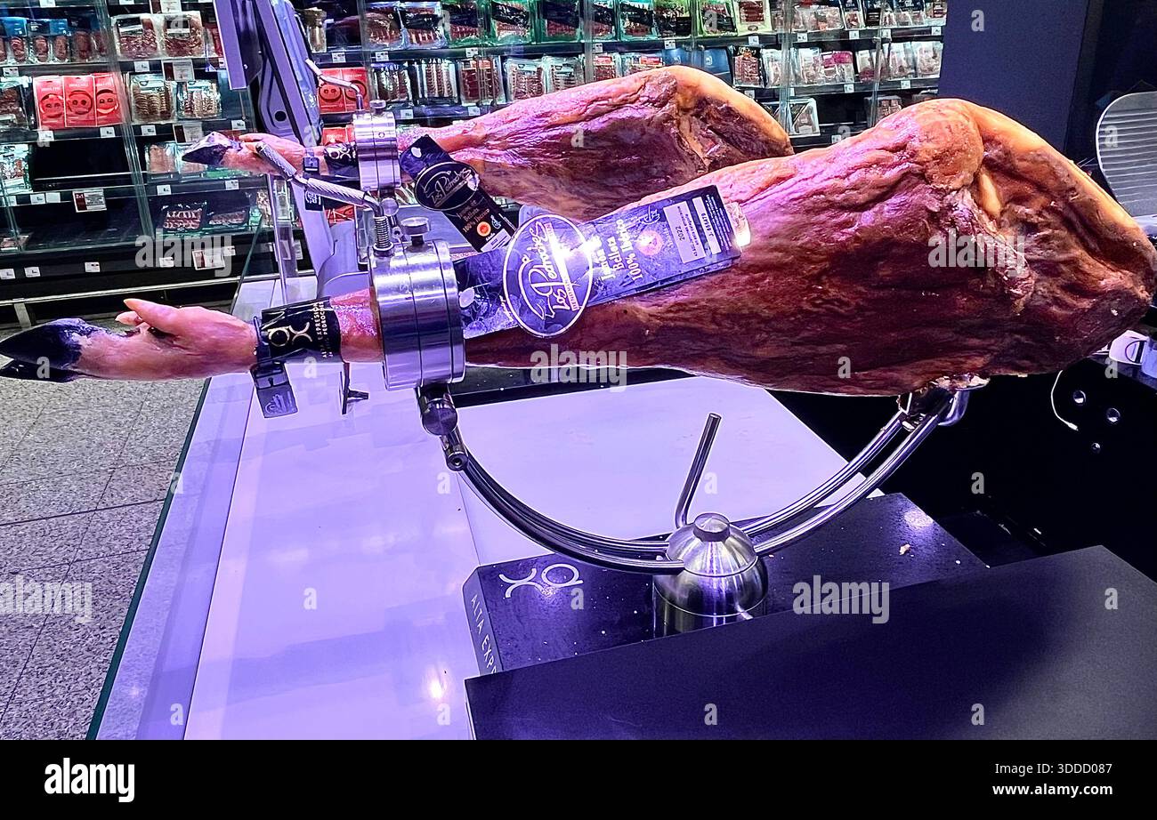 Los Pedroches Jamón serrano bellota 100% Ibérico dry-cured ham legs on jamonero stands for sale 179 euros a kilo in a Spanish supermarket at Christmas - Smartphone Captured Stock Image