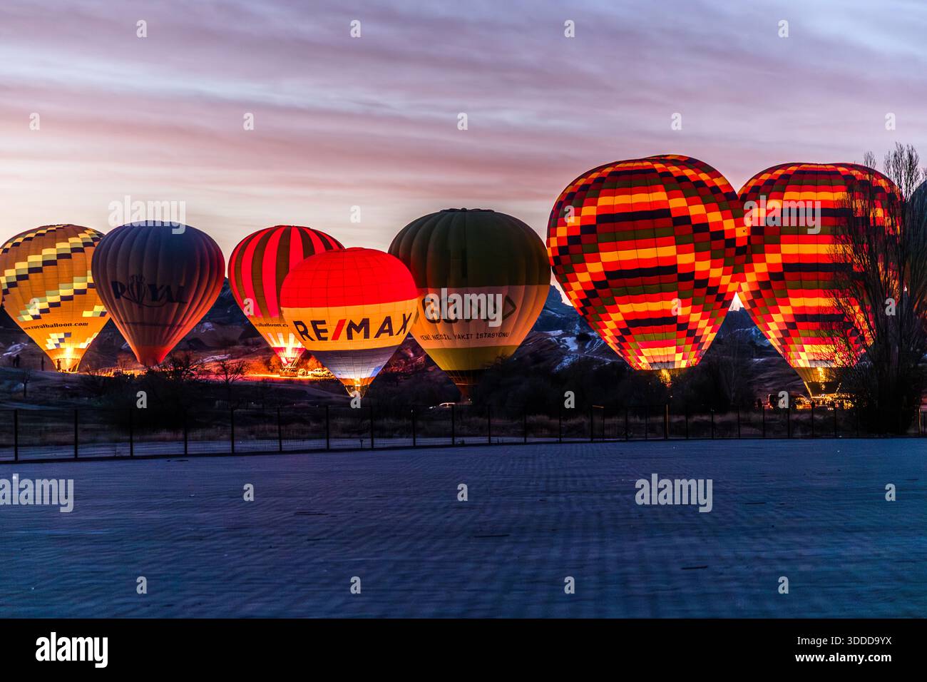 Several hot air balloons glow before take-off in Cappadocia at dawn near Göreme, Central Anatolia Region, Turkey Stock Photo