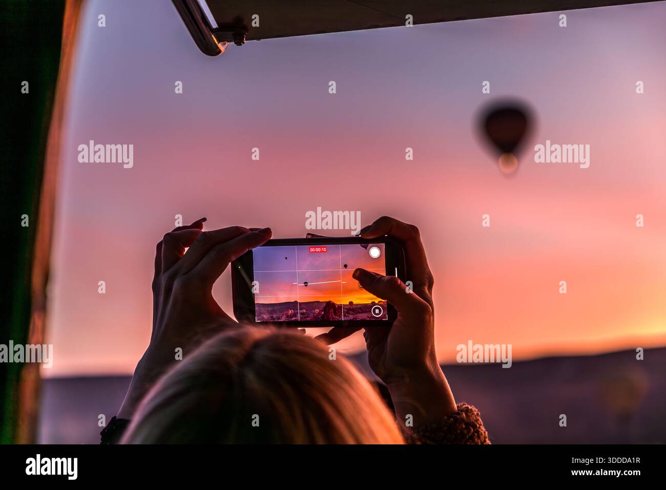 Woman films hot air balloons at sunrise in Göreme with her smartphone, Central Anatolia Region, Turkey Stock Photo