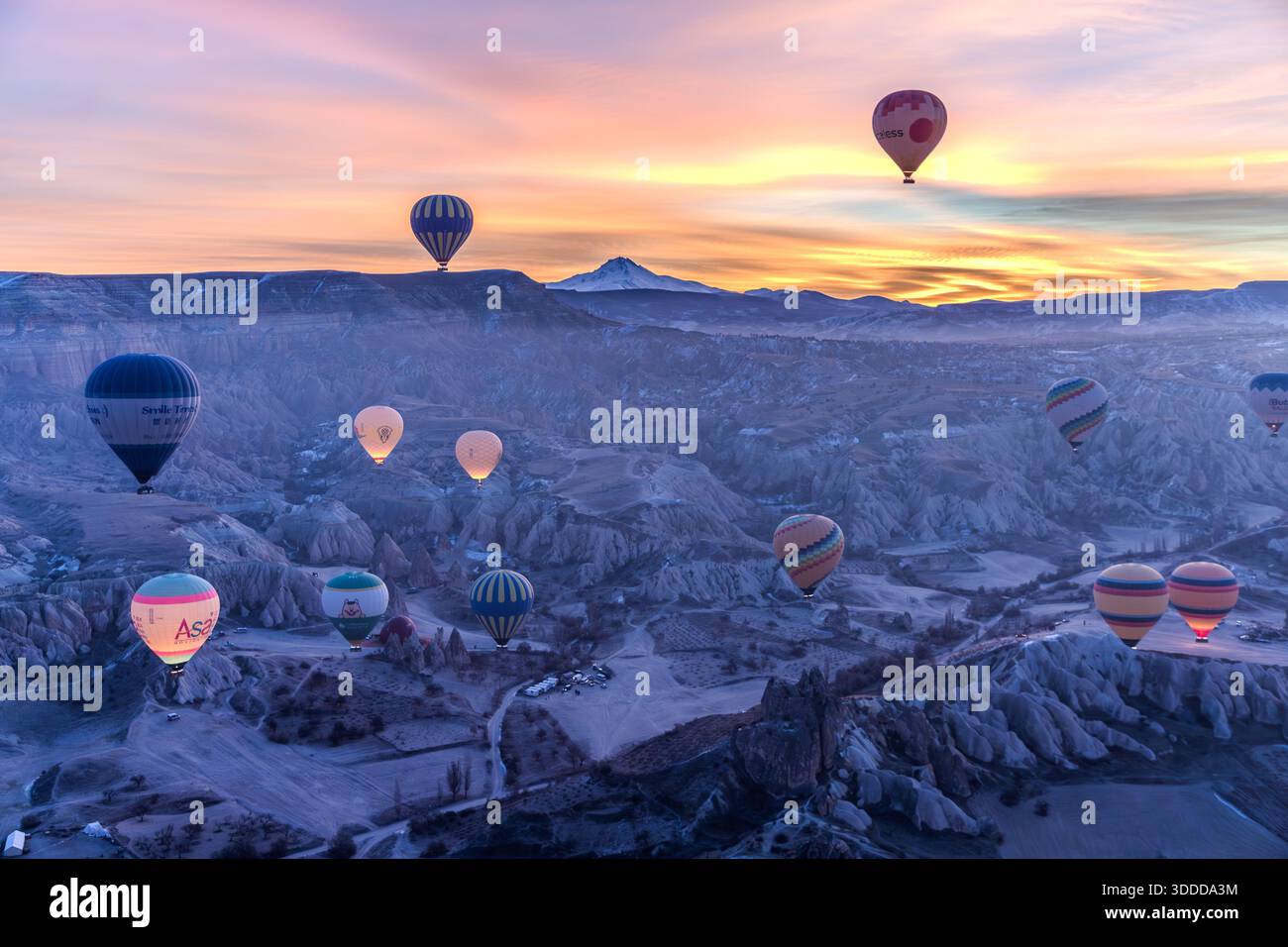 Shortly before sunrise behind the Erciyes Dağı volcano, hot air balloons float over the tuff landscape of Cappadocia. Göreme, Central Anatolia Region, Turkey Stock Photo