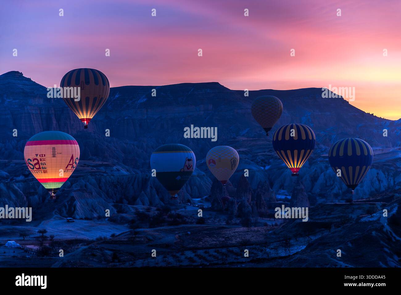 Hot air balloons rise above the rock formations of Göreme at sunrise, Central Anatolia Region, Turkey. Tuff stone landscape and fairy chimneys Stock Photo